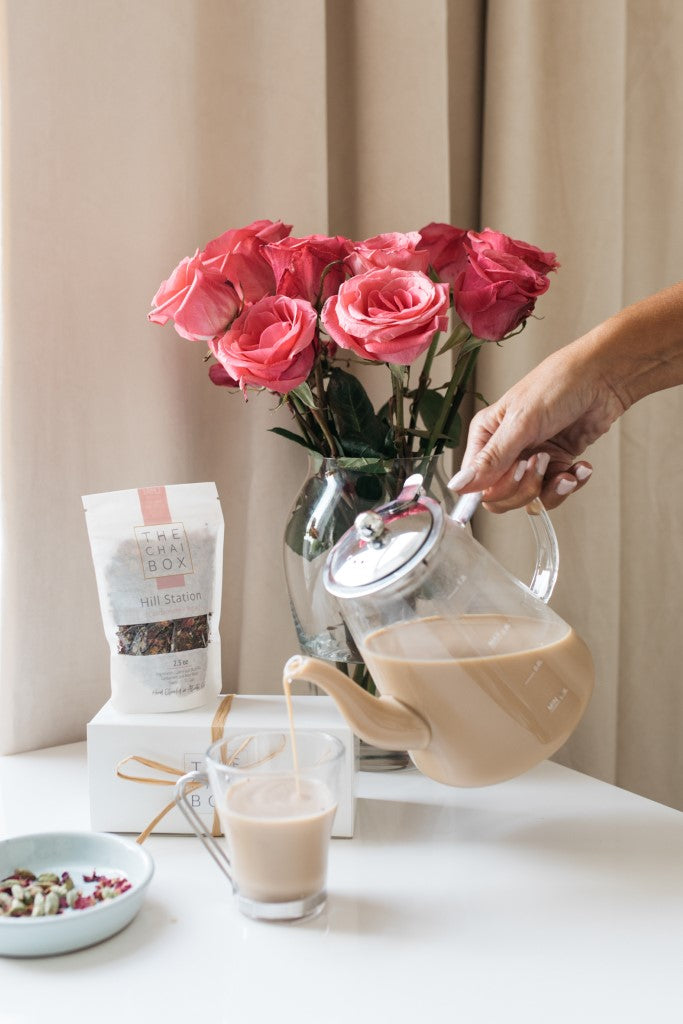 Hill Station Chai being poured in a glass cup. Blend of Cardamon and Rose