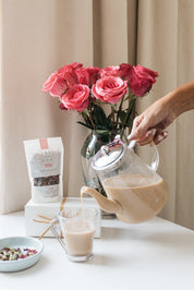 Hill Station Chai being poured in a glass cup. Blend of Cardamon and Rose