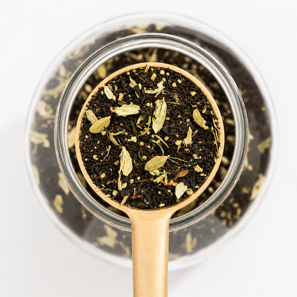 Tea leaves in a glass jar with a gold spoon