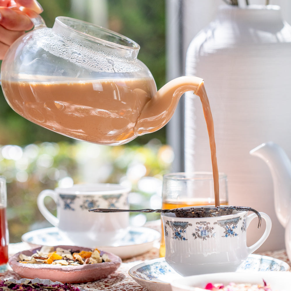 Hot Chai being poured from a kettle into a cup made with organic tea and premium spices