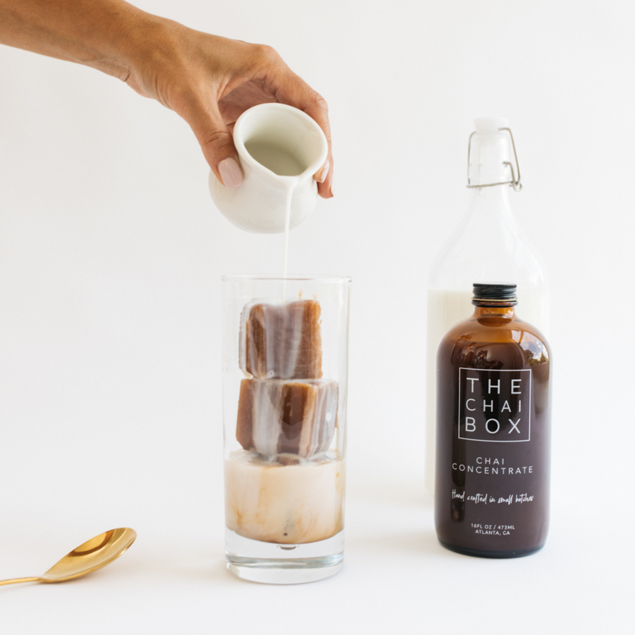Milk being poured over ice cubes made with Chai Concentrate. The chai box concentrate is a convenient way to make iced chai. Ethical and Sustainable chai. 